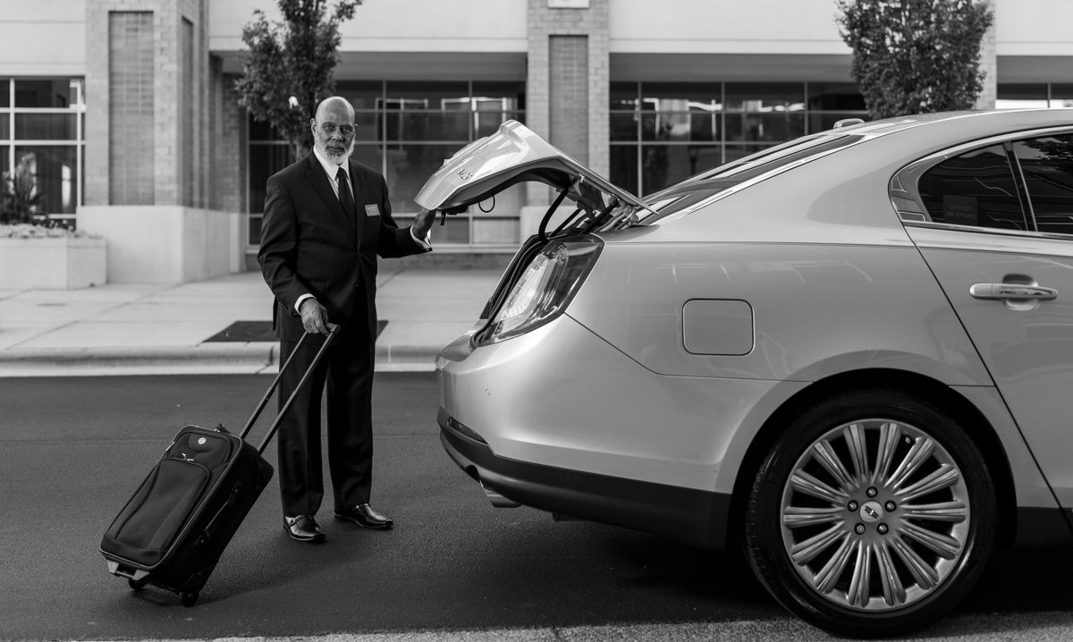 Chauffeur tilt een koffer in de kofferbak van een personenauto