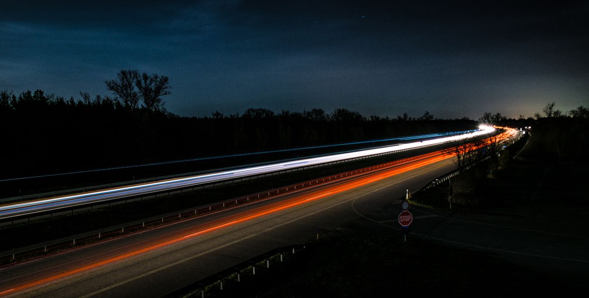 Lange sluitertijd van een auto op een donkere snelweg in de avond