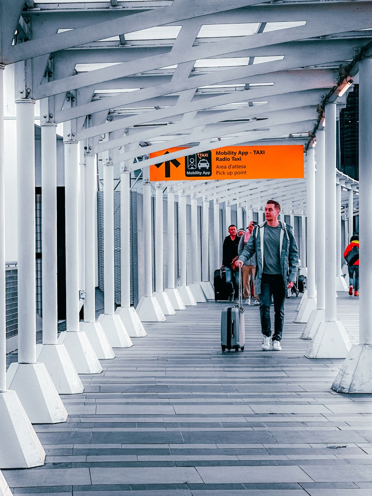 Reizigers met koffers in een lichte loopbrug naar de vertrekhal